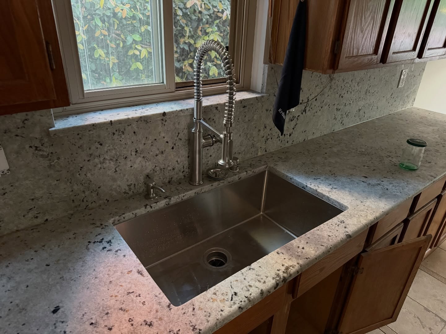 A plumber working on a residential water fixtures job — mid-task, hands, tools and the work itself in sharp focus, the rest of the space softly out of focus