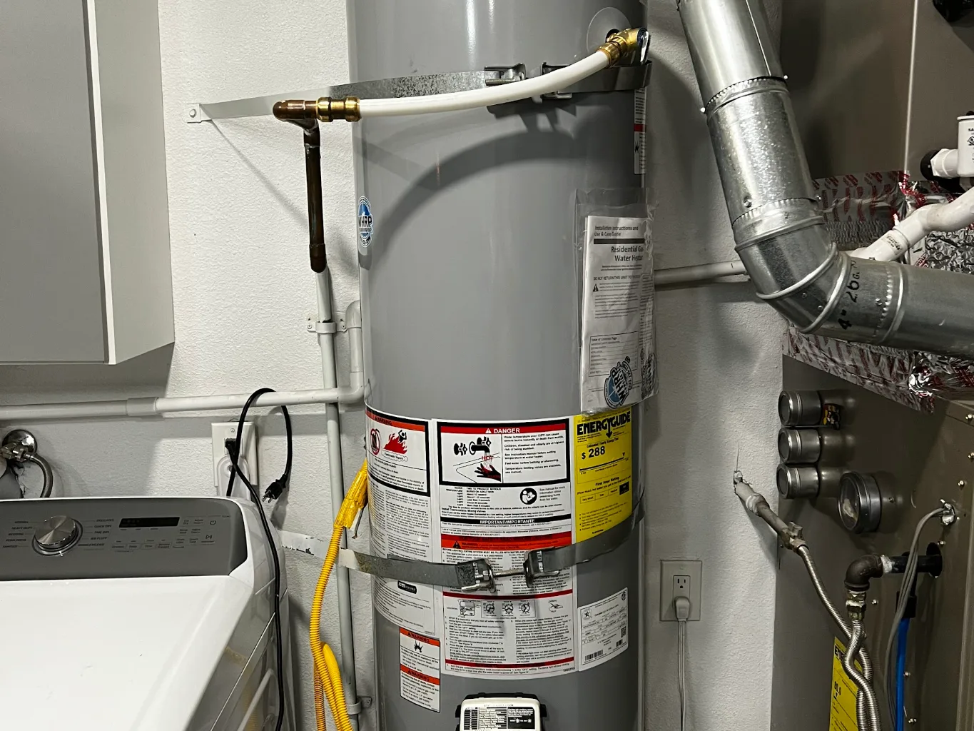 A plumber working on a residential water heaters job — mid-task, hands, tools and the work itself in sharp focus, the rest of the space softly out of focus